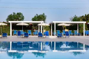 un gruppo di sedie e ombrelloni accanto alla piscina di Dolmen Sport Resort a Minervino di Lecce