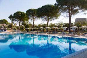 una grande piscina con sedie e ombrelloni di Dolmen Sport Resort a Minervino di Lecce
