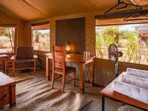 Tulia Amboseli Safari Camp في أمبوسيلي: غرفة مع طاولة وكراسي في خيمة