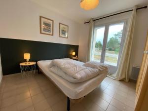 un letto in una camera con una grande finestra di Les Amourettes - 2 min à pied Plage - Jardin a La Faute-sur-Mer