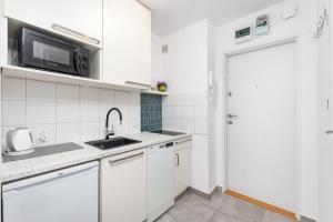 a white kitchen with a sink and a microwave at Broniewskiego 24A by Homeprime in Warsaw