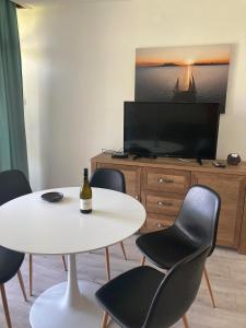 a living room with a white table and chairs and a tv at Attila Beach Boglár in Balatonboglár