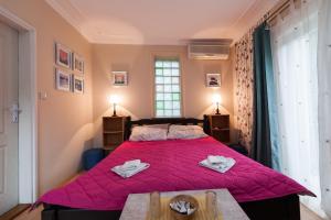1 dormitorio con 1 cama grande con manta rosa en Vila Eden Palić, en Palić