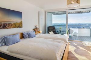 a bedroom with a large bed and a large window at Bodenseepanorama Oberuhldingen in Uhldingen-Mühlhofen +34 photos