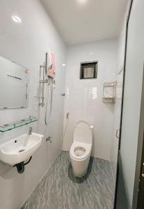 a white bathroom with a toilet and a sink at Family Homestay Quy Nhon in Quy Nhon