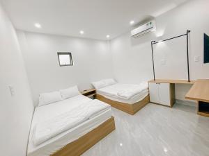 a white room with two beds and a mirror at Family Homestay Quy Nhon in Quy Nhon