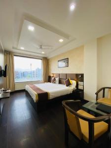 Hotel SS Grandeur في Alambagh: غرفة فندقية بسرير وطاولة ونافذة