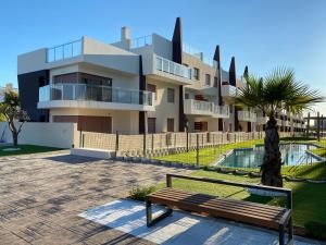 un banco del parque frente a un edificio en Bianca Beach 222 - Mil Palmeras, vista piscina y mar, en Torre de la Horadada