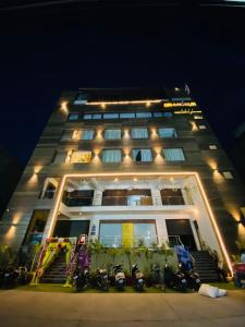 Hotel SS Grandeur في Alambagh: مبنى به دراجات نارية متوقفة أمامه في الليل