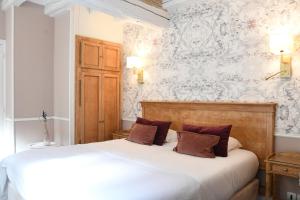 a bedroom with a white bed and a white wall at Le Moulin Des Ruats in Avallon