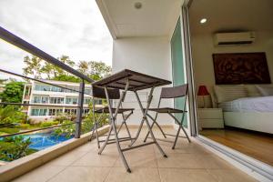 Balcón con cama, mesa y 2 sillas en Hill Side Karon Kata Beach Condo en Phuket