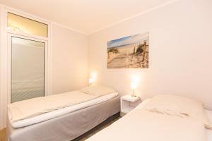 2 Betten in einem weißen Zimmer mit Fenster in der Unterkunft Kurpark-Residenz 125 in Döse