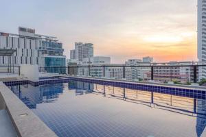 a swimming pool on top of a building with a city at Citismart Residence in Pattaya