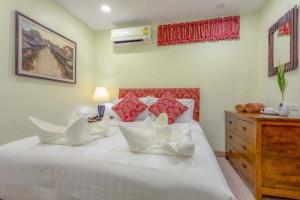 Una cama blanca con almohadas y un tocador en un dormitorio. en Citismart Residence en Pattaya Central