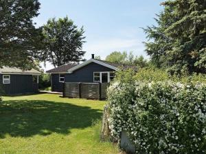 a blue house in a yard with a hedge at 8 person holiday home in Hesselager in Hesselager