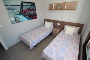 una habitación con 2 camas y una foto de un coche en Casa D'Alessandro, en Orihuela Costa