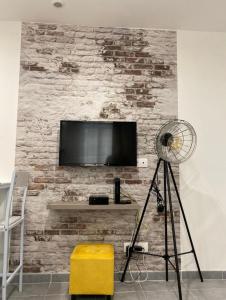 uma sala de estar com televisão numa parede de tijolos em Studio 23m2 moderne hypercentre - Arènes à 2 min em Nîmes