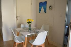 a dining room table with white chairs and a vase of flowers at Pelican Cottage - 800m from Beach & Yacht School in Hout Bay +22 photos