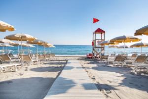 a beach with chairs and umbrellas and the ocean at Hotel Village Paradise in Mandatoriccio Marina