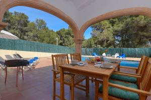 un patio con mesa, sillas y piscina en Monte Naranja, en Jávea