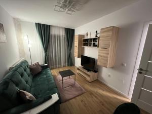 a living room with a green couch and a television at Aparthotel Junior4 Cluj in Cluj-Napoca