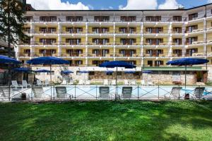 a hotel with tables and chairs with blue umbrellas at Grand Hotel del Parco in Pescasseroli