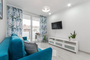 een woonkamer met een blauwe bank en een tv bij Apartament Baltic Sun in Sztutowo