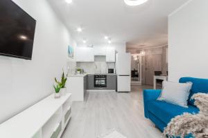 a living room with a blue couch and a kitchen at Apartament Baltic Sun in Sztutowo