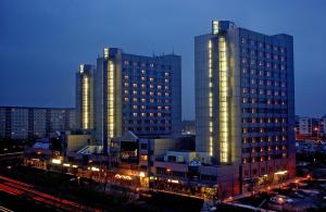 twee hoge gebouwen in een stad 's nachts bij City Hotel Berlin East in Berlijn