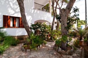 a garden with trees and plants in front of a building at Apartamentos MHM in Cala Ratjada