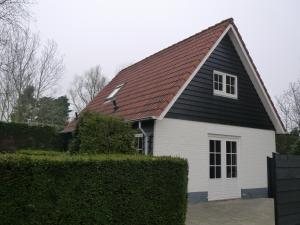 een wit en zwart huis met een zwart dak bij De Wentehoeve in Oostkapelle