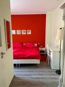 1 dormitorio rojo con 1 cama con pared roja en die Senfbude - schöne, ebenerdige 2-Raum-Apartments mit Stellplatz und Terrasse, en Leipzig