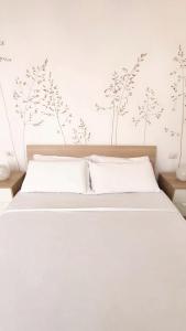 um quarto com uma cama com lençóis brancos e árvores na parede em B&B Le Albarelle em Alba