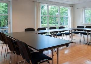 un gruppo di tavoli e sedie in una stanza con finestre di Lille Grynborg a Blommenslyst