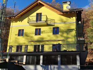 une maison jaune avec un balcon sur le côté. dans l'établissement Casa Firmina Appartamento Santa Maria Maggiore, à Santa Maria Maggiore