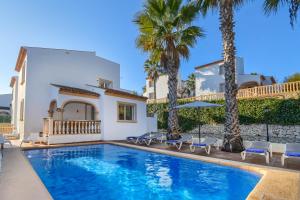 a villa with a swimming pool and palm trees at Monte Violeta in Jávea