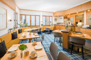 ミュンヘンにあるホテル アム ノックヘアベルクのテーブルと椅子のあるレストラン、キッチンが備わります。