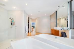 a white bathroom with a tub and a sink at Swainson on Waymouth - Penthouse in Adelaide +14 photos