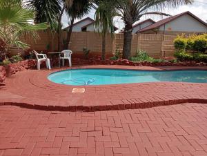 a small swimming pool with two chairs and a table at KnB Guesthouse in Rustenburg
