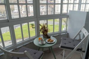 a table and chairs in a room with windows at Padrón Suites in Padrón