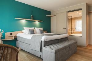 Boutique Hotel 'Hof ter Duinen' في أوستدوينكيرك: غرفة نوم بسرير كبير وجدار ازرق
