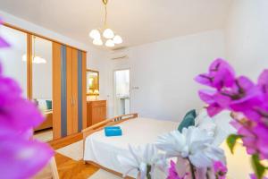 1 dormitorio con 1 cama con flores púrpuras en el primer plano en Family Apartment close to the Beach en Mlini