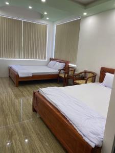 a room with two beds and two chairs in it at Khách sạn Gia Nghiêm in Ấp Trà Kha