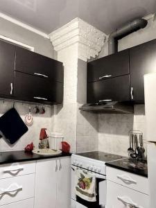 a kitchen with white appliances and black cabinets at Квартира in Ustʼ-Kamenogorsk