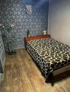 a bedroom with a bed with a black and white comforter at Квартира in Ustʼ-Kamenogorsk