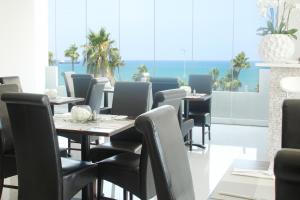 a dining room with tables and chairs and the ocean at Achilleos City Hotel in Larnaca