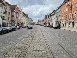 una calle de la ciudad con vías de tren en el medio en Maximilianstraße en Augsburg