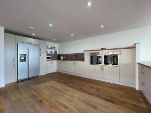 a large kitchen with white appliances and wooden floors at Balloan Steading East in Dornoch