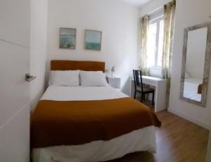 a bedroom with a bed and a desk and a mirror at Apartamento Roco in Madrid