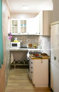 Apartment Welcome في Karaburma: مطبخ فيه دواليب بيضاء وثلاجة بيضاء